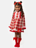 Child wearing a Spanish red, beige and white checkered dress with red bows.