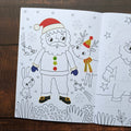 Coloring book page with Santa Claus and reindeer on a wooden surface
