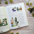 Open book with illustrated fairy tale pages on a wooden surface with decorative elements.