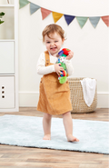 Child holding a colorful toy in a room with a colorful banner and wicker basket.