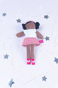 Doll with a white top and red skirt on a light gray background with star shapes