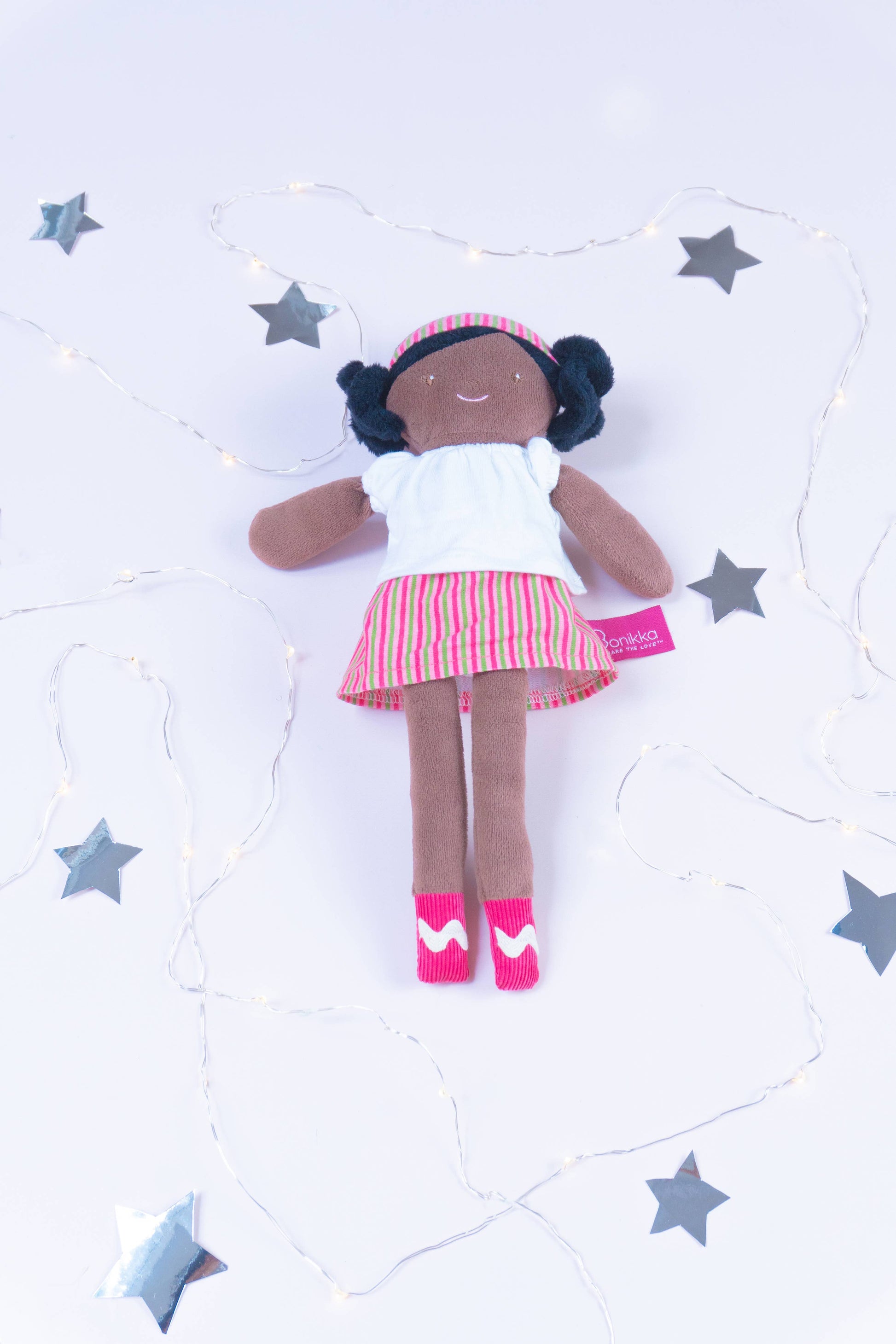 Doll with a white top and red skirt on a light gray background with star shapes