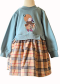Children's outfit with blue sweater and plaid skirt on a mannequin against a white background
