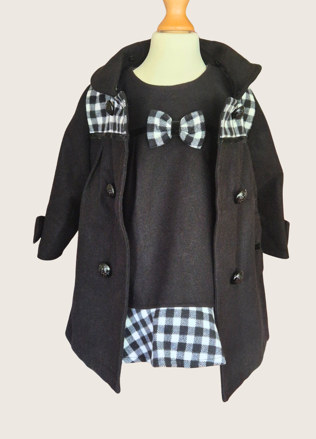 Black coat with plaid pattern on a mannequin against a plain background