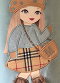Embroidered patch of a girl in a plaid skirt and hat with a 'M' bag on a light blue background