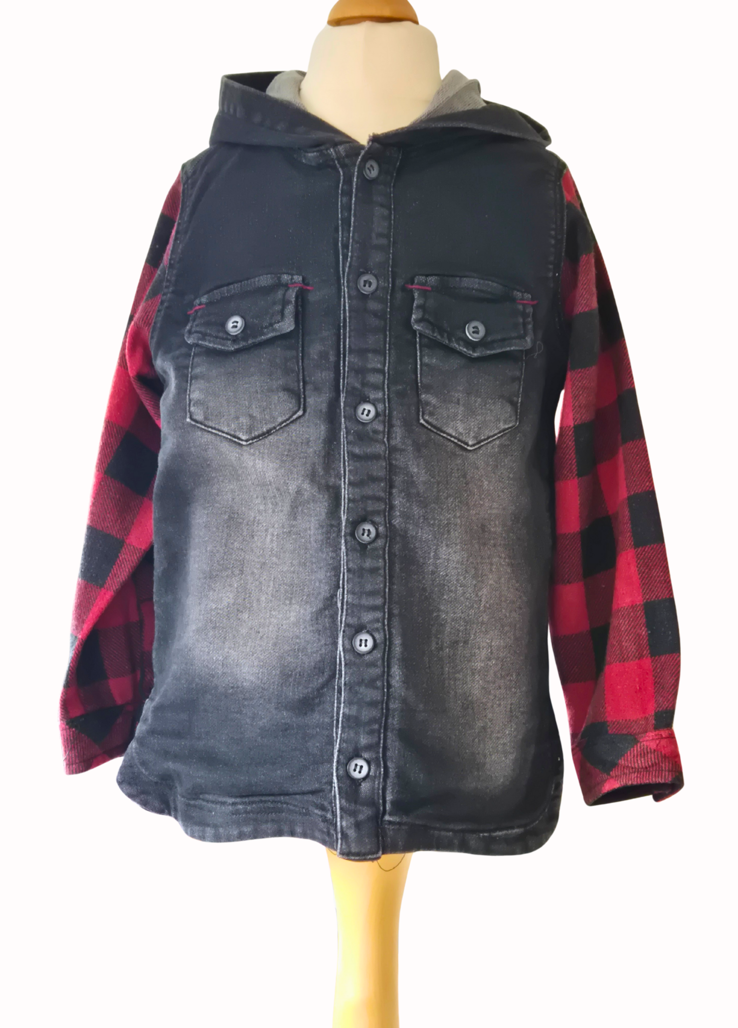 Denim shirt with plaid sleeves on a mannequin against a white background