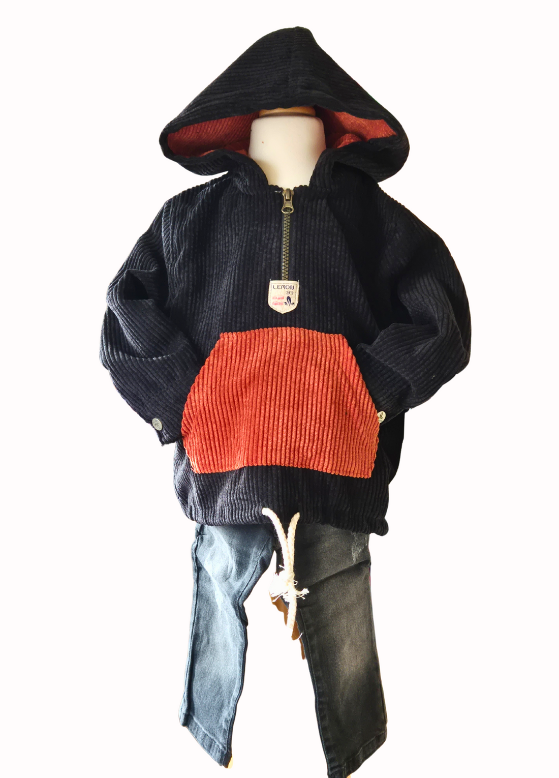 Black distressed jeans and a black and rust cord hoodie on a mannequin against a white background