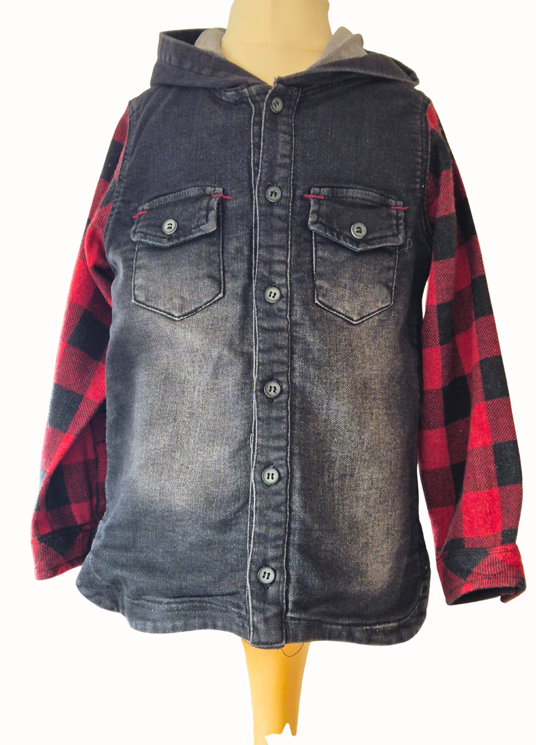 Denim shirt with red plaid sleeves on a mannequin against a white background