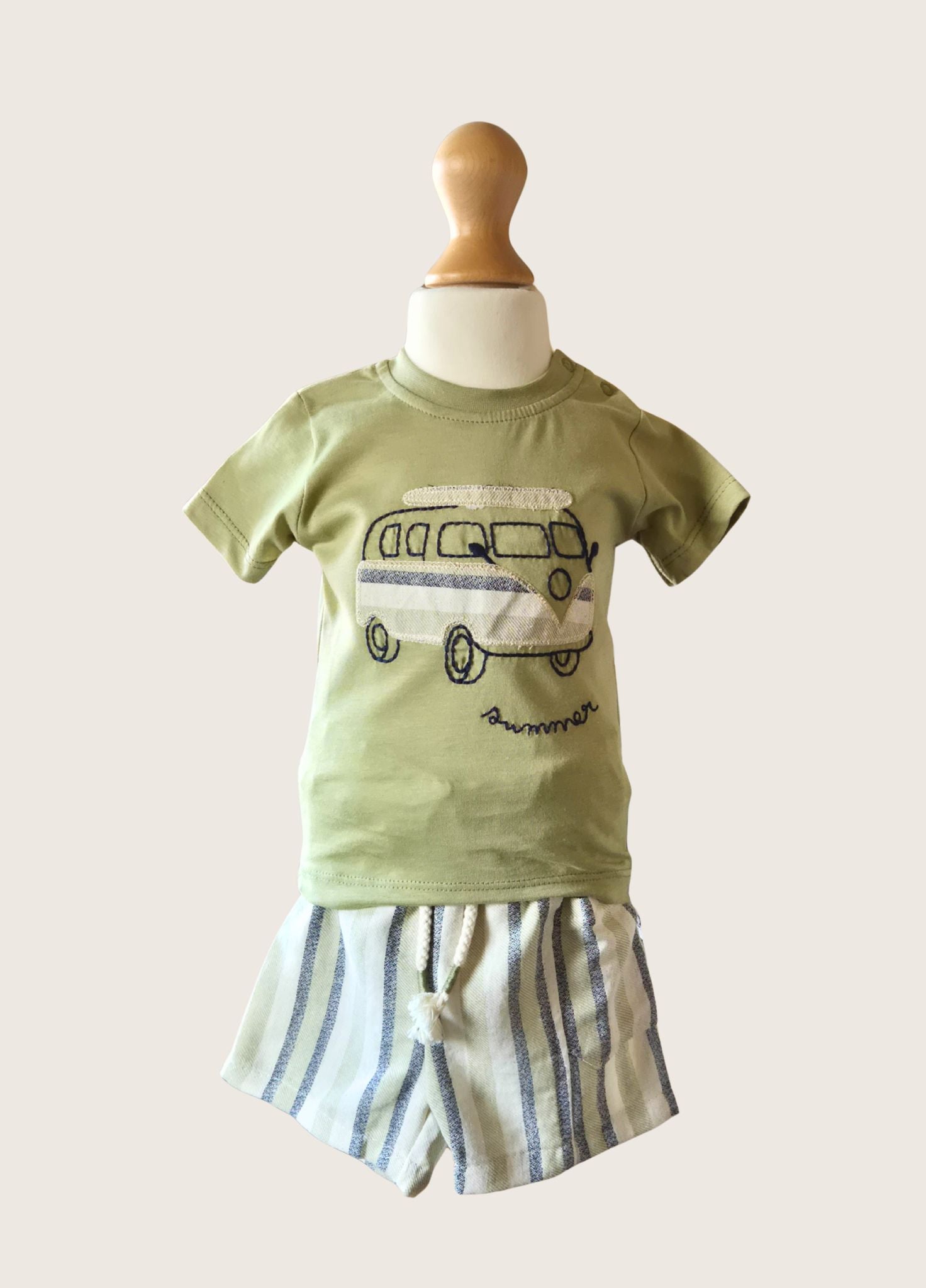 Children's green t-shirt with graphic design and striped shorts on a mannequin against a white background