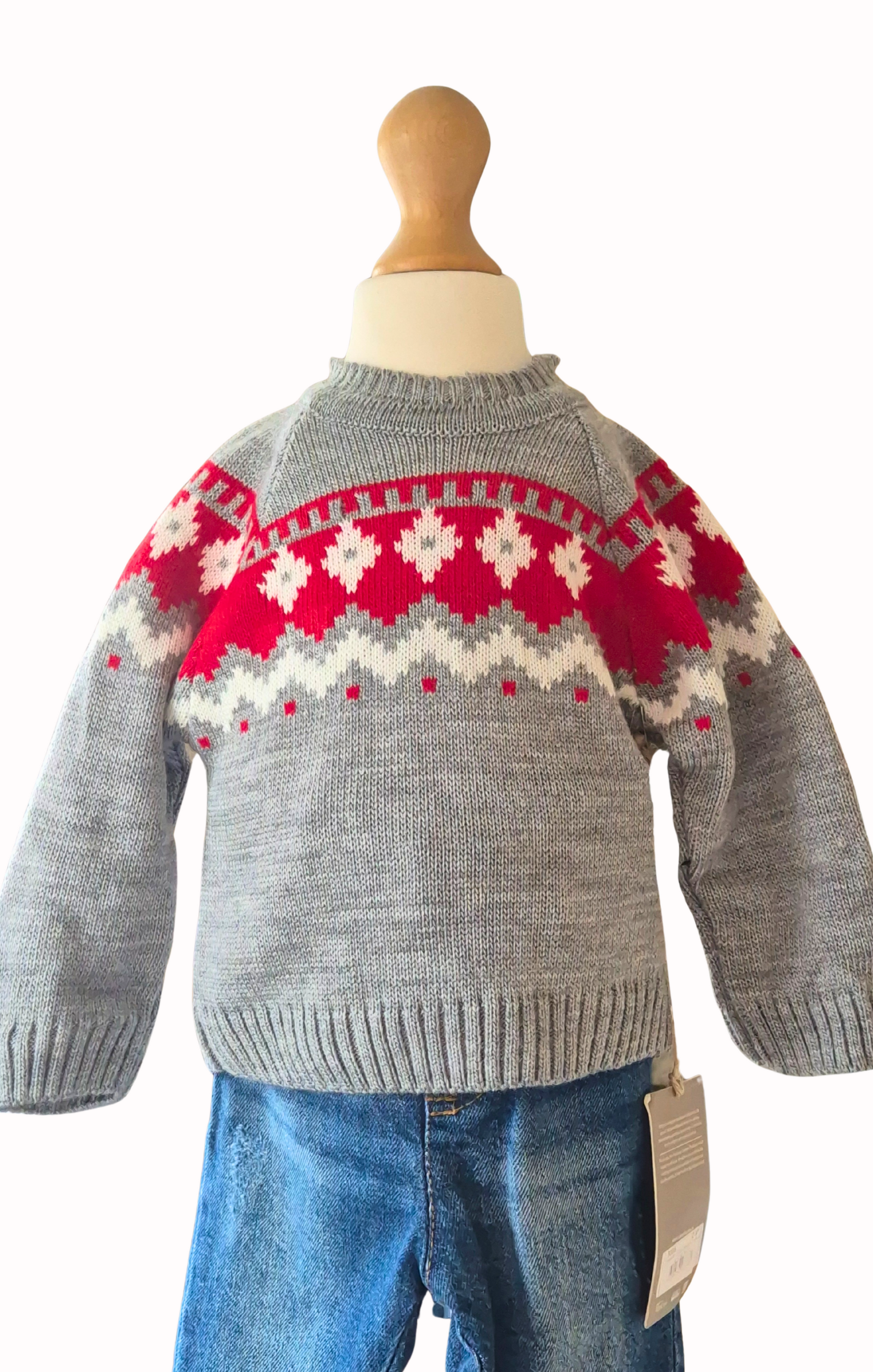 Close up of gray sweater with red and white pattern on a mannequin against a white background