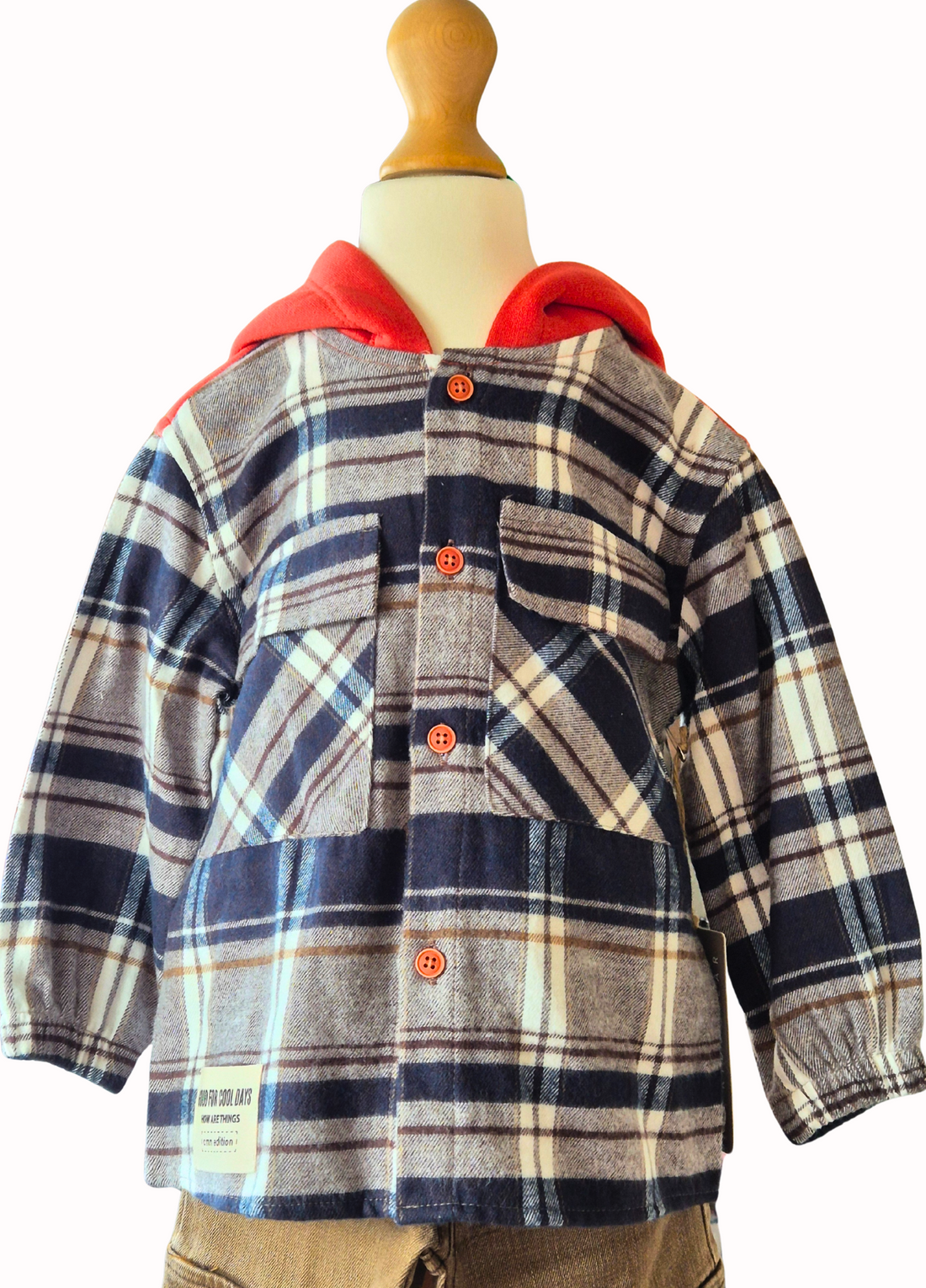 Children's plaid shirt with orange hood and beige pants on a mannequin against a white background