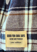 Plaid fabric with a label reading 'Good for cool days, how are things cmm edition' on a checkered background.