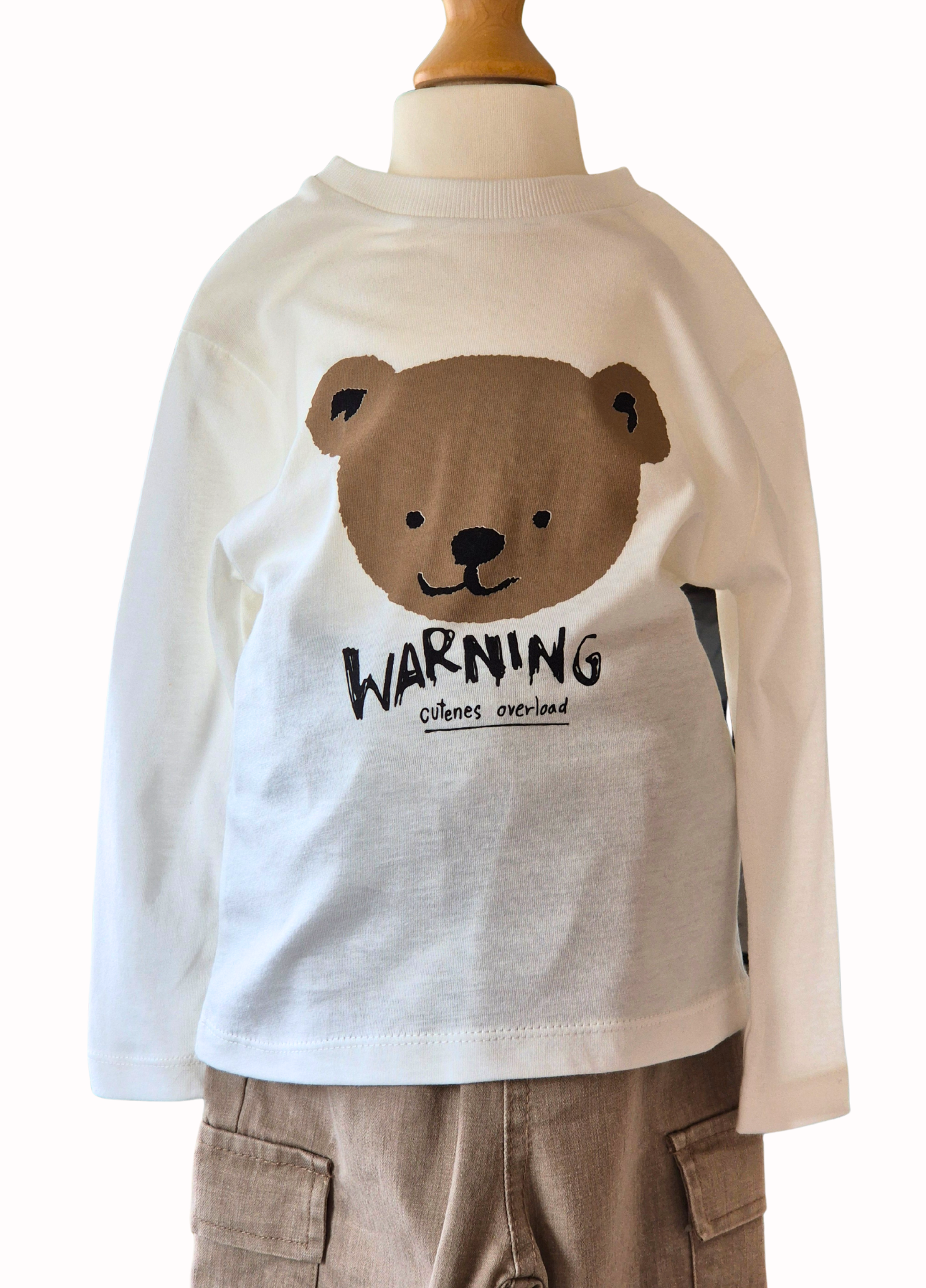 Children's long-sleeve shirt with bear graphic and 'WARNING cuteness overload' text on a mannequin.