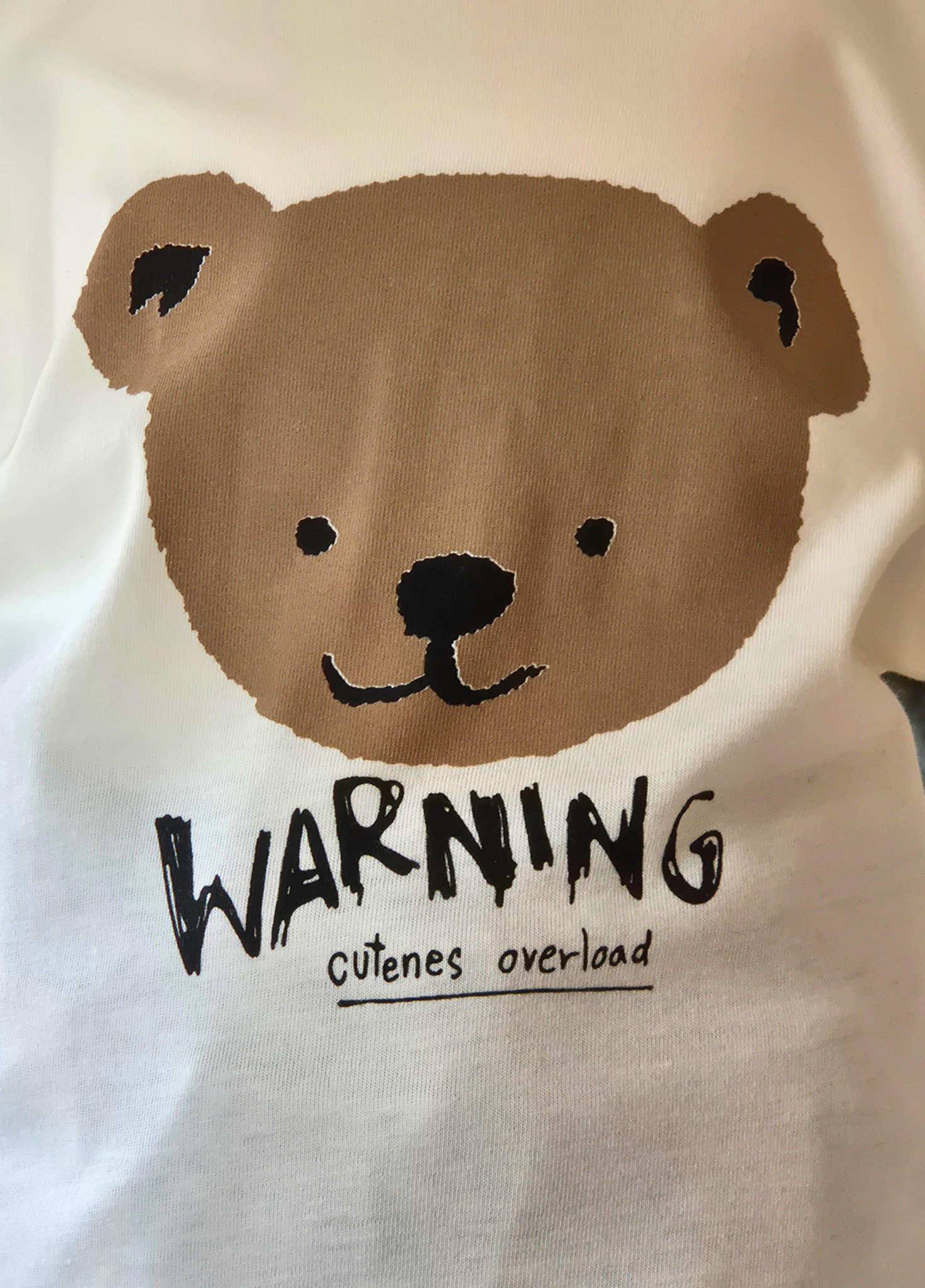 White shirt with a bear face design and 'WARNING: Cuteness overload' text.
