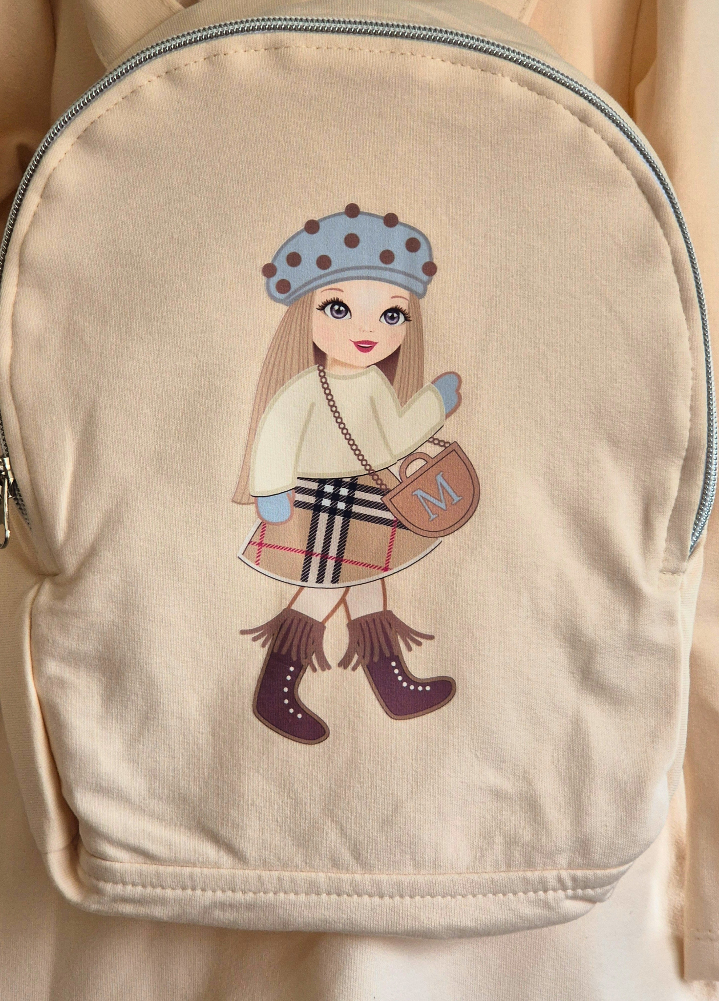 Beige backpack with a cartoon character design on a beige background