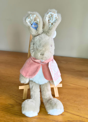 Plush Flopsy rabbit toy with a pink cape on a wooden surface