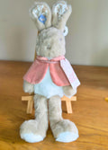 Plush Flopsy rabbit toy with a pink cape on a wooden surface