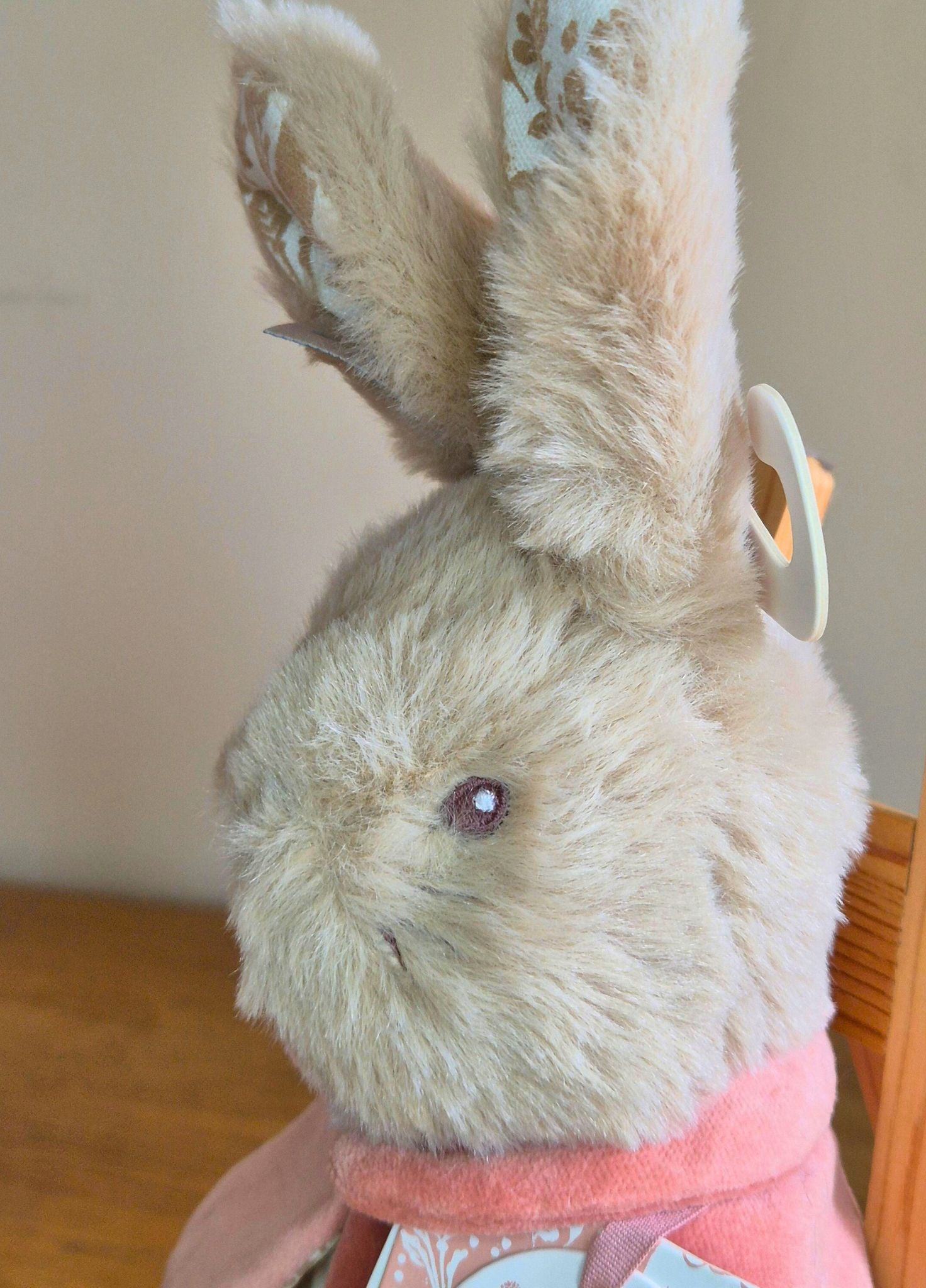 Plush  Flopsy rabbit toy with a pink cape on a wooden surface