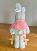 Back of Flopsy Rabbit stuffed toy with her pink cape on a wooden surface