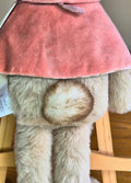 Close-up of Flopsy Rabbit plush toys tail wearing a pinkcape on a wooden surface