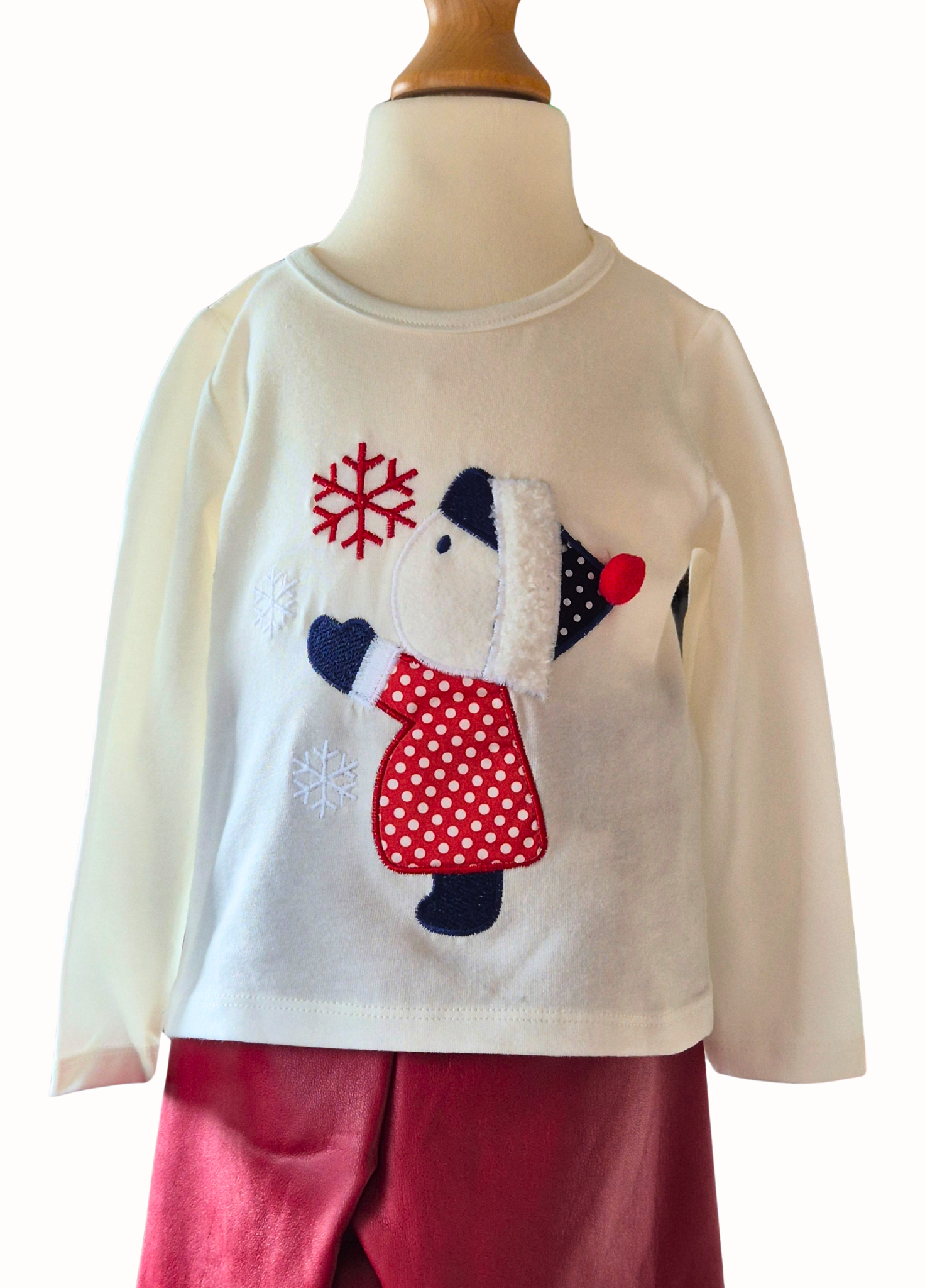 Children's outfit with a white top featuring a little girl design and red pants on a mannequin.