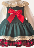 Close up of Spanish Green dress with red plaid skirt, red bow, and lace details/