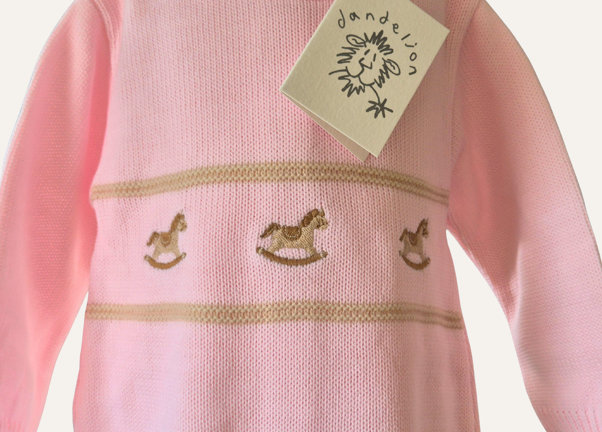 Close up of rocking horse detail on a baby pink knitted romper from Dandelion