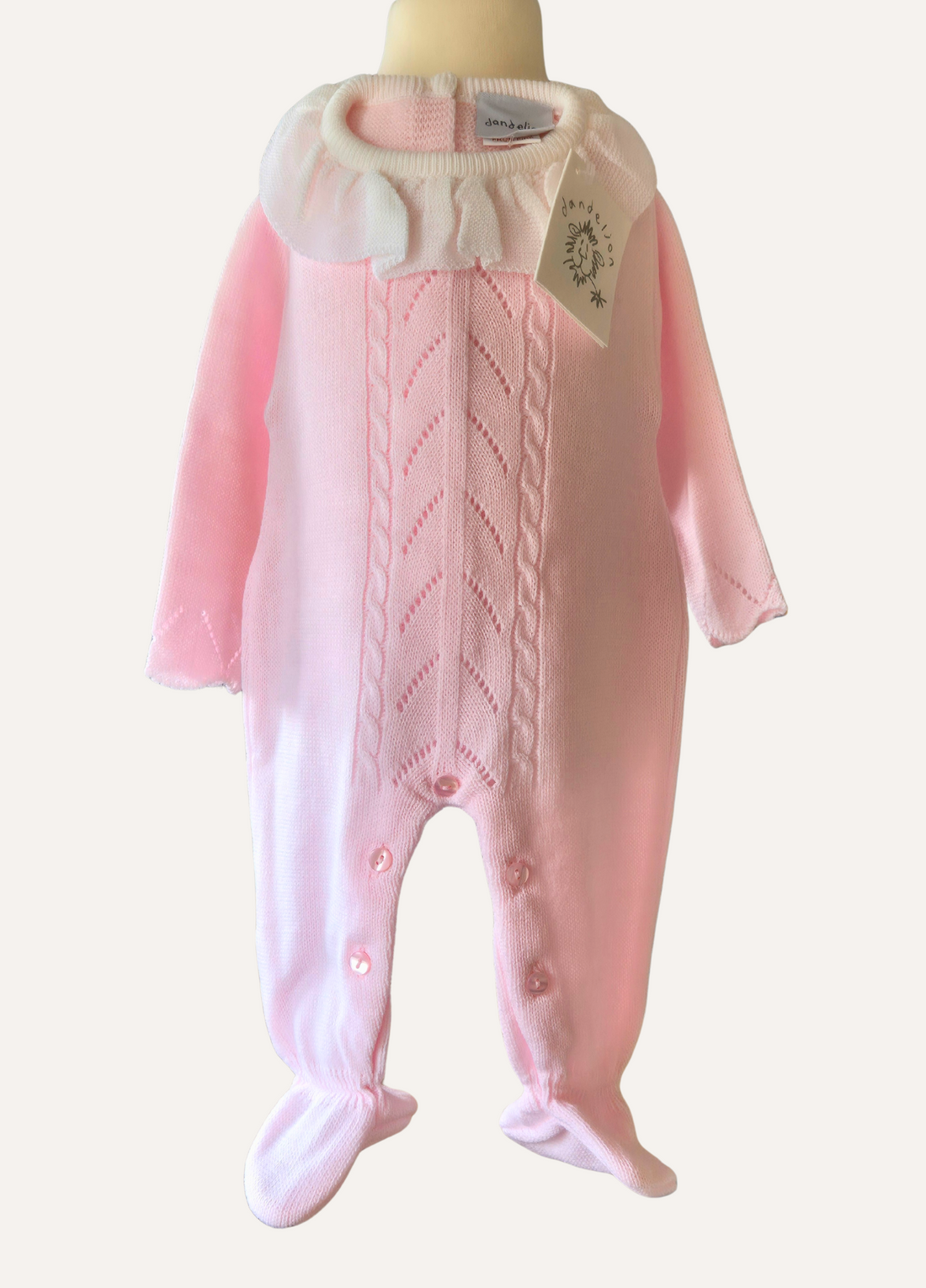 Baby pink knitted romper with cable and lace detail and a white collar with matching bonnet from Dandelion