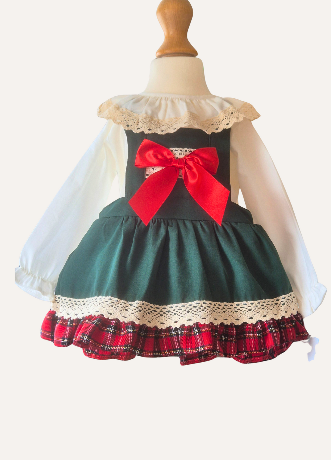Children's dress with plaid skirt and red bow on a mannequin against a white background