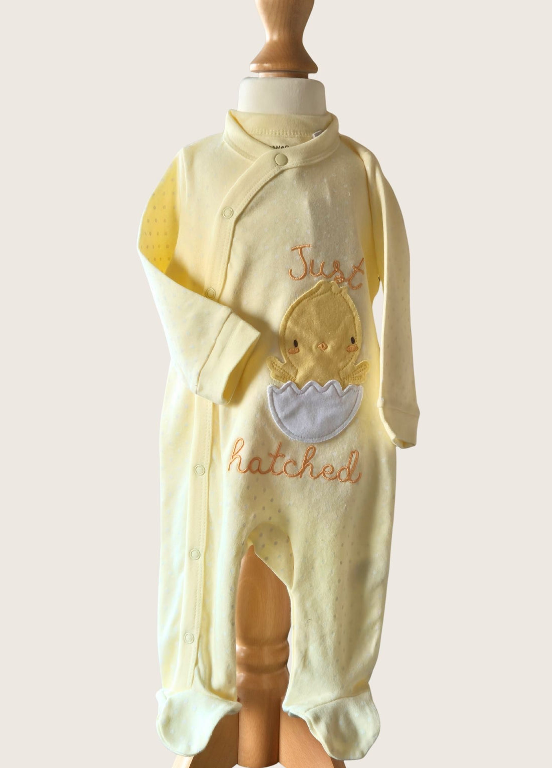 Baby in lemon Just Hatched Sleep Suit with a Chick comine out of a cracked Egg