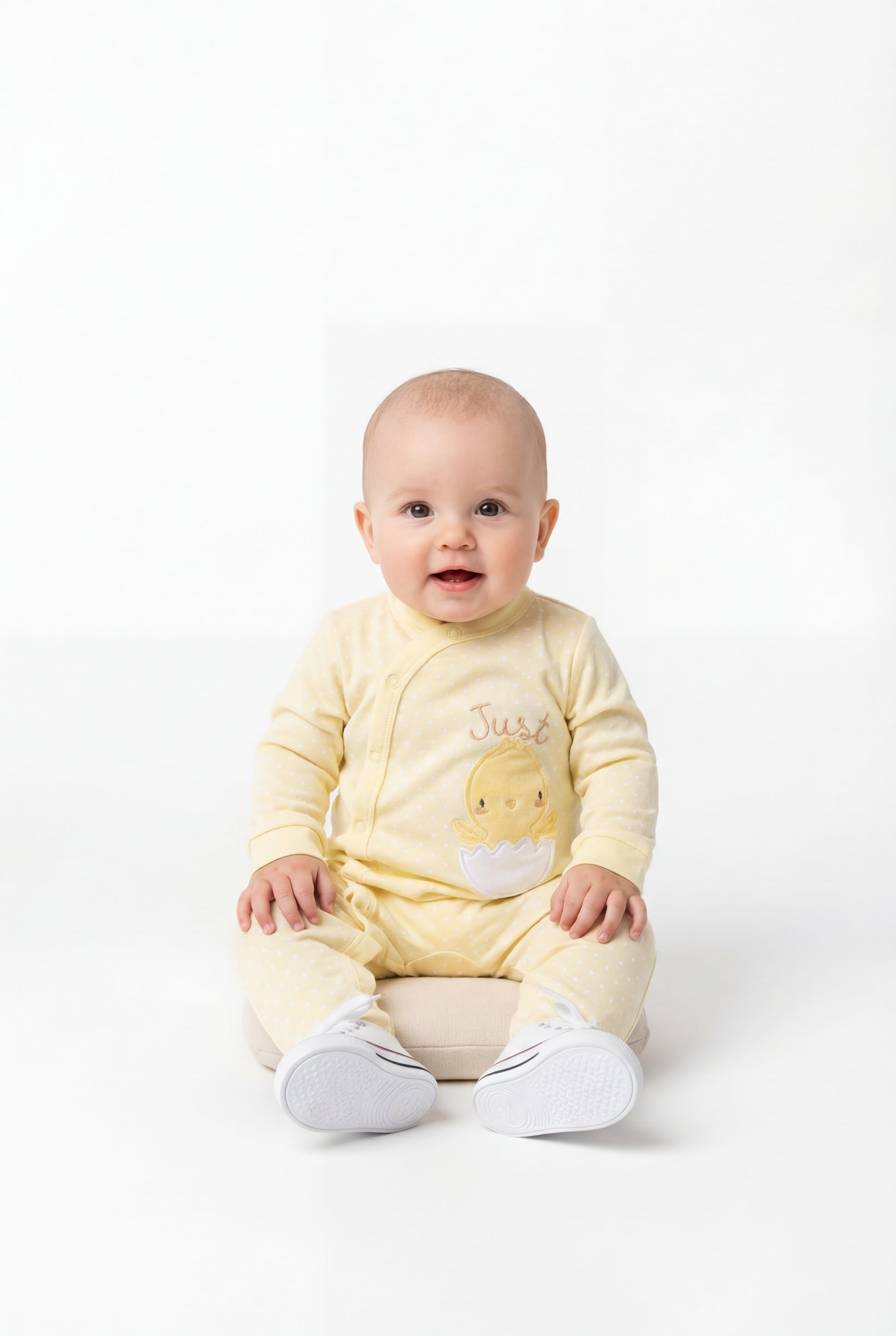 Baby wearing a yellow onesie with a cartoon design on a white background
