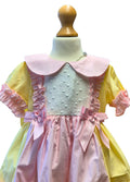 Pastel-colored dress with ruffled sleeves and collar on a mannequin against a white background