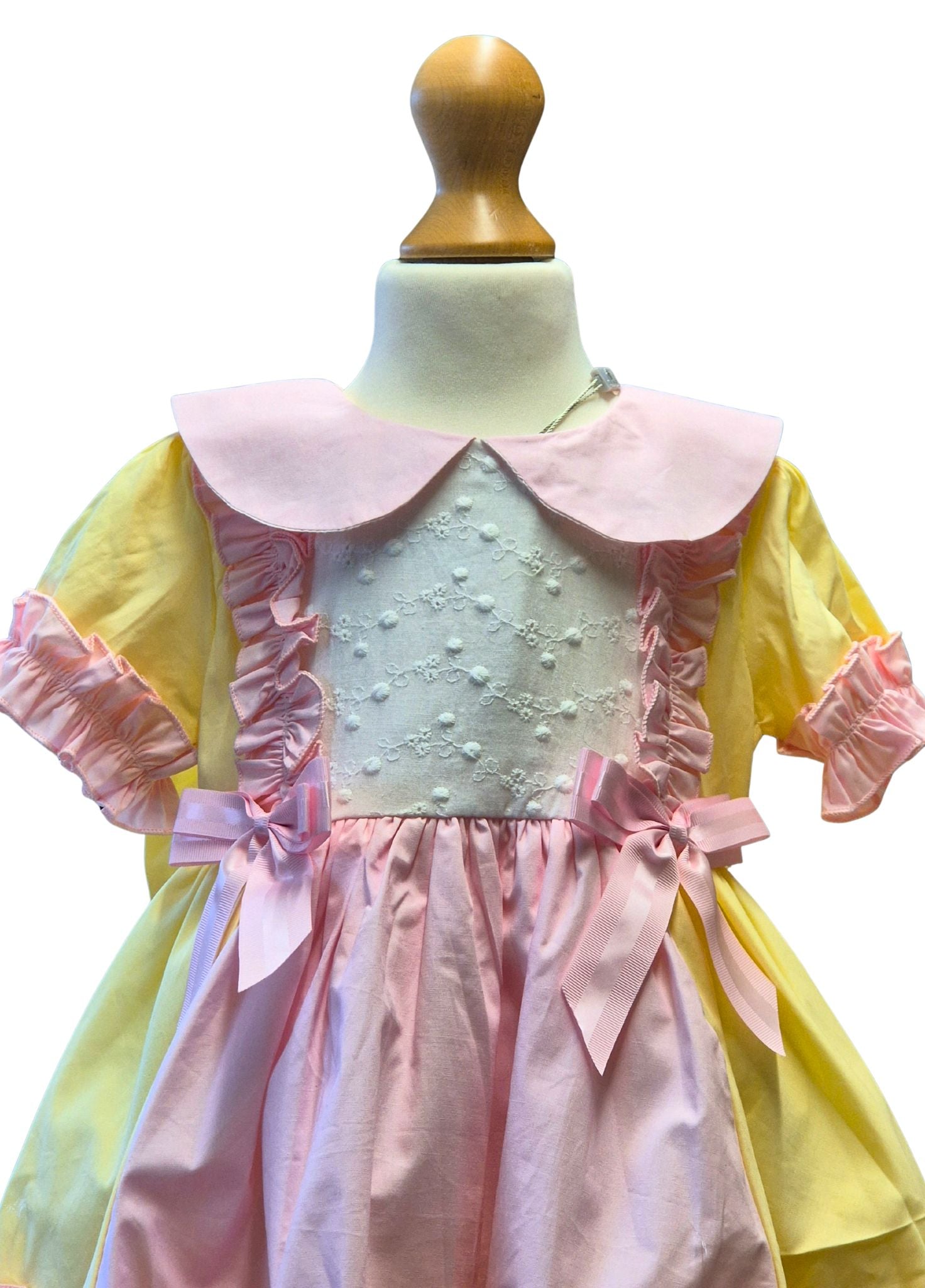 Pastel-colored dress with ruffled sleeves and collar on a mannequin against a white background