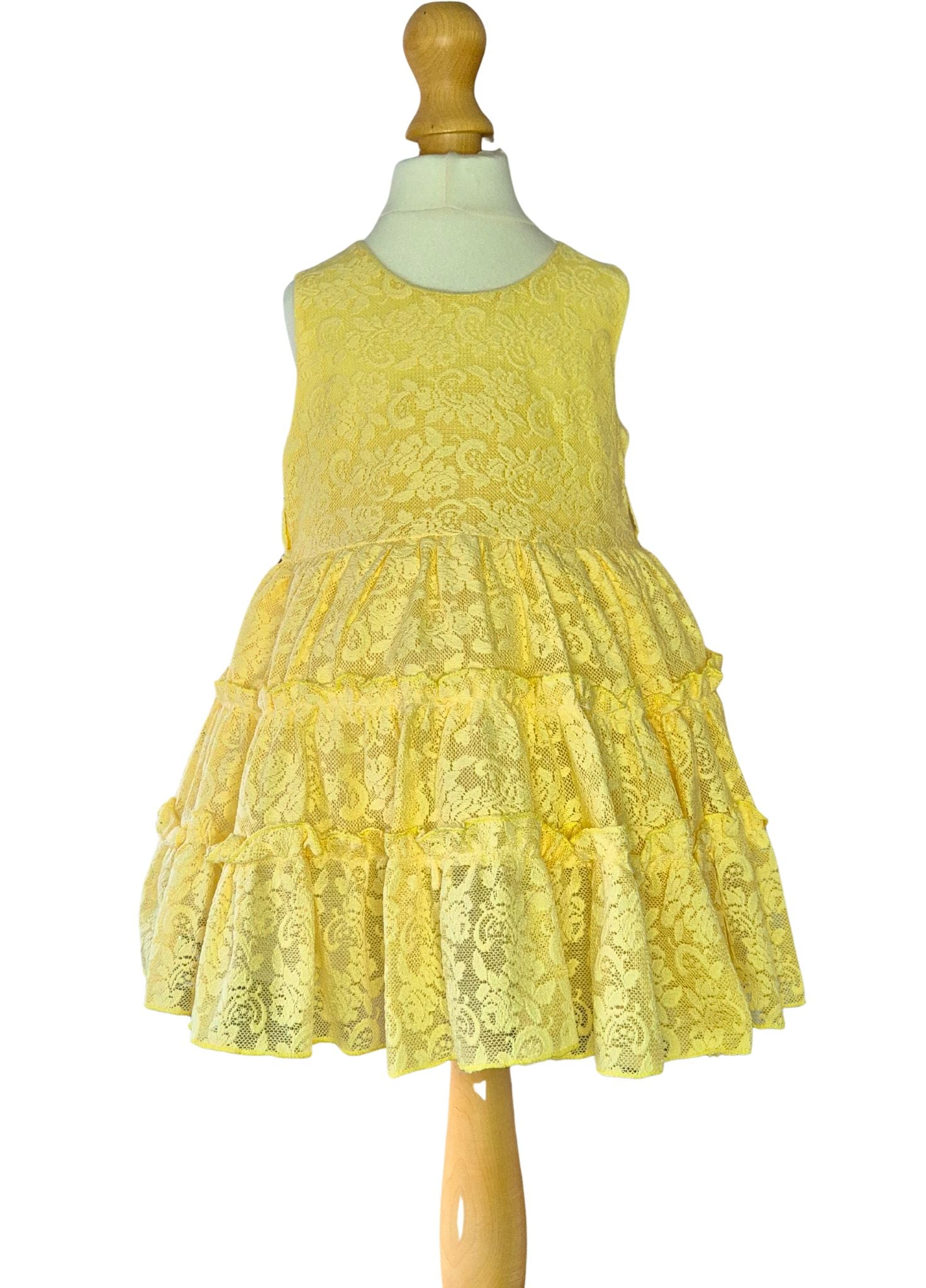 Yellow lace dress on a mannequin against a white background