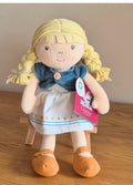 Organic  ragdoll with blonde hair and a blue bolero jacket on a wooden stool with a plain background