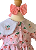 Pink dress with cherry pattern and large bow on a mannequin against a white background
