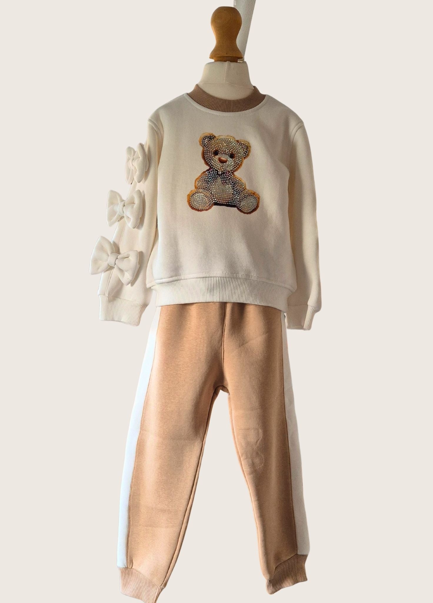Children's outfit with a sweater featuring a teddy bear design on a mannequin against a white background.