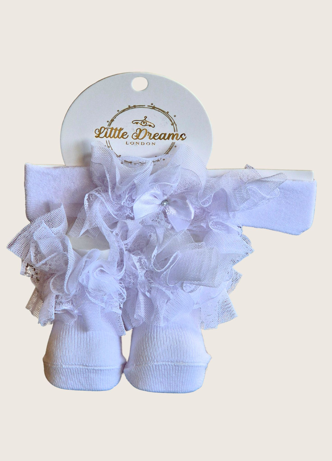 White baby socks with ruffles on and  a matching headband on a white background, branded 'Little Dreams London'.