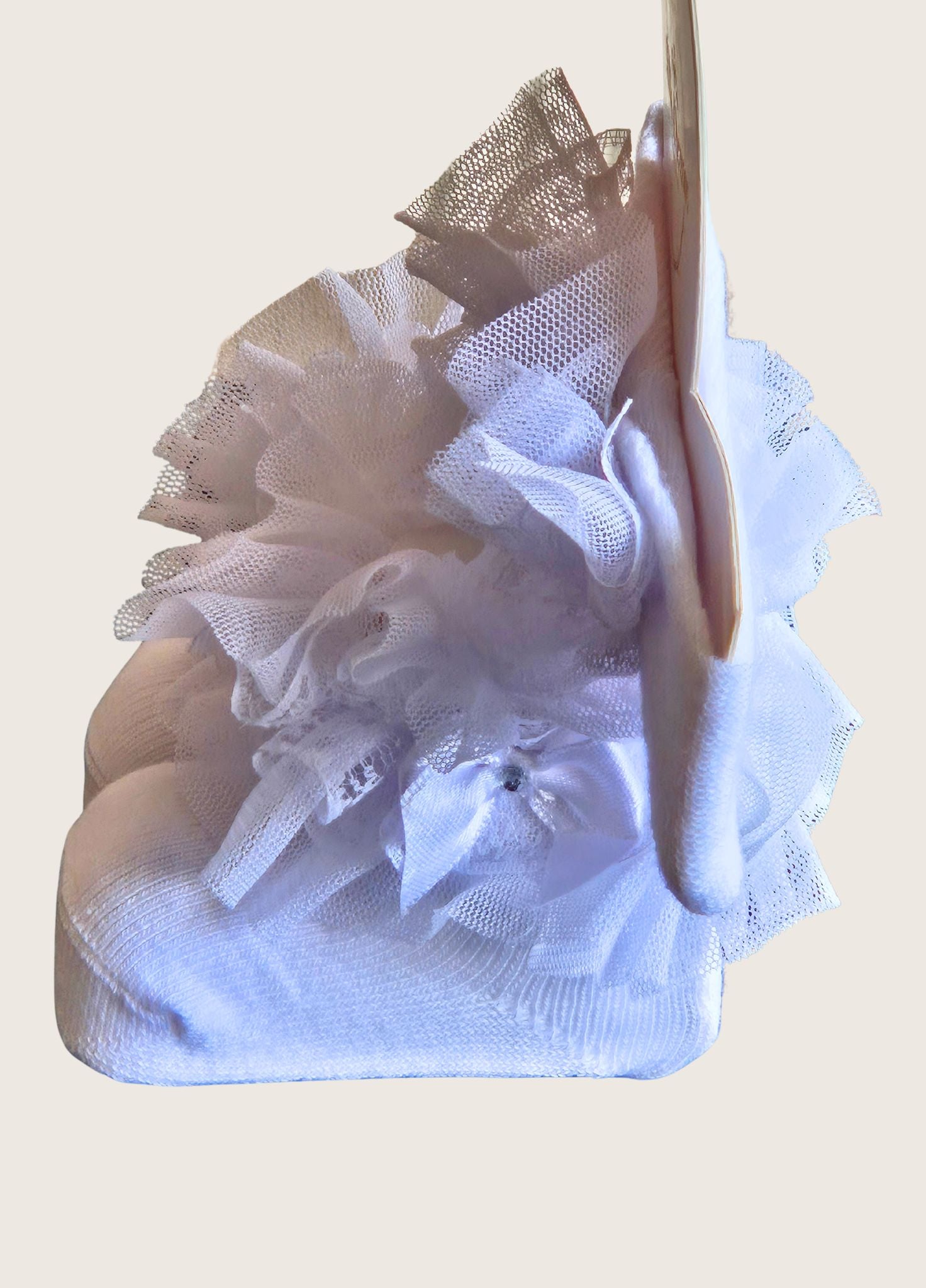 White lace baby socks with a bow and a matching headband on a beige background