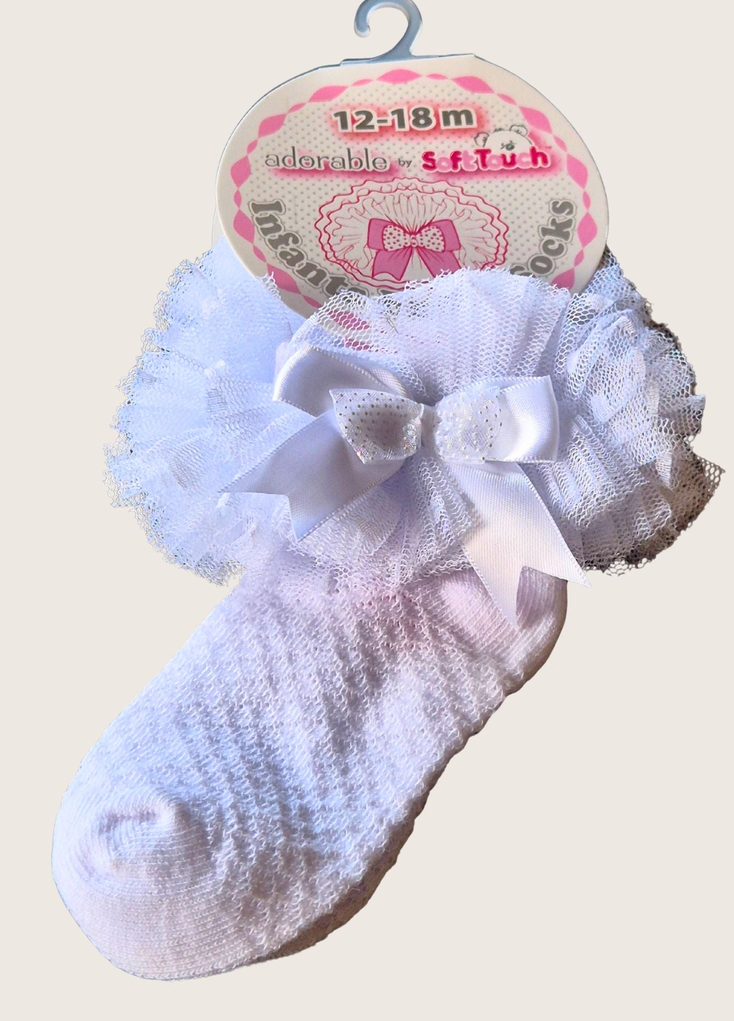 White baby socks with a bow on a pink and white packaging label.