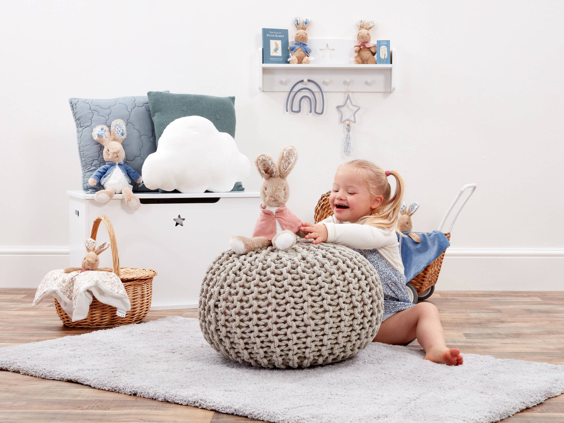 Child playing with Flopsy Rabbit  on a pouf in a room with decorative items.
