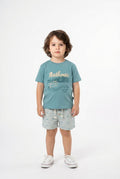 Child wearing a blue t-shirt with text and shorts on a white background