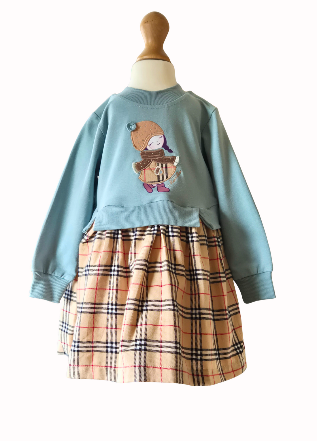 Children's outfit with blue sweater and plaid skirt on a mannequin against a white background