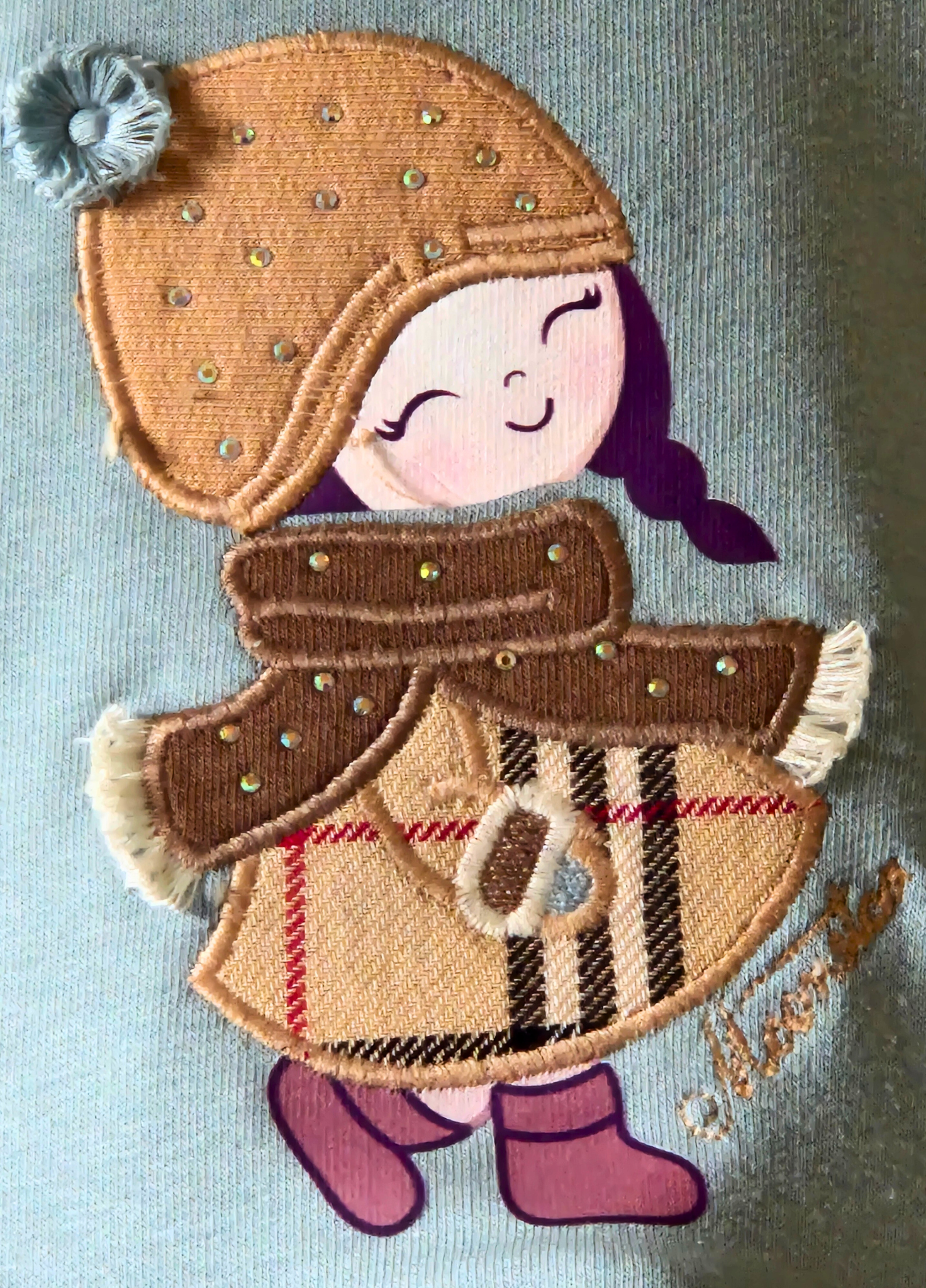 Embroidered patch of a girl in winter clothing on a light blue background