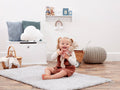 Child sitting on a rug in a room with toys and furniture