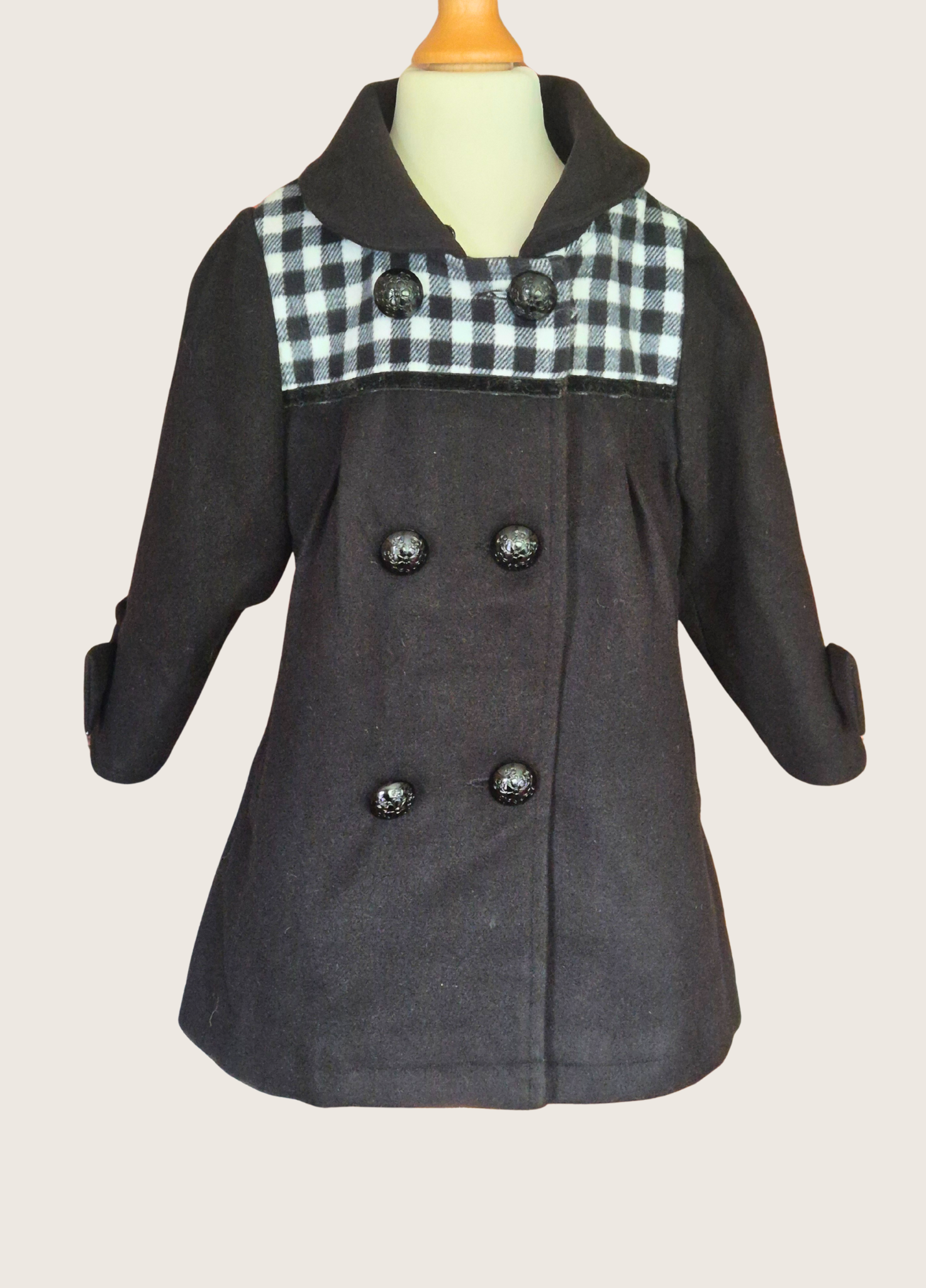 Black coat with plaid collar on a mannequin against a beige background