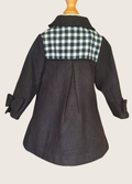 Back view of black coat with checkered pattern on a mannequin against a beige background