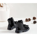 Back view of a pait of shiny black patent boots styled on a white background with pinecones and a white vase.