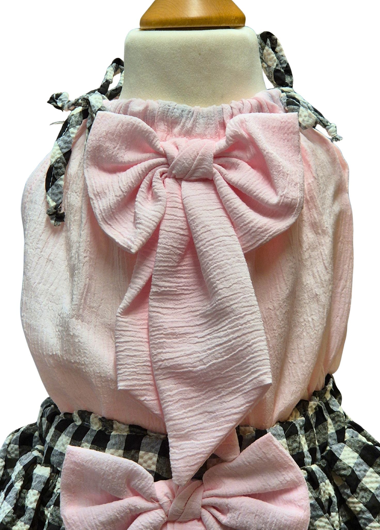 Pink textured topwith a large bow on a mannequin against a white background