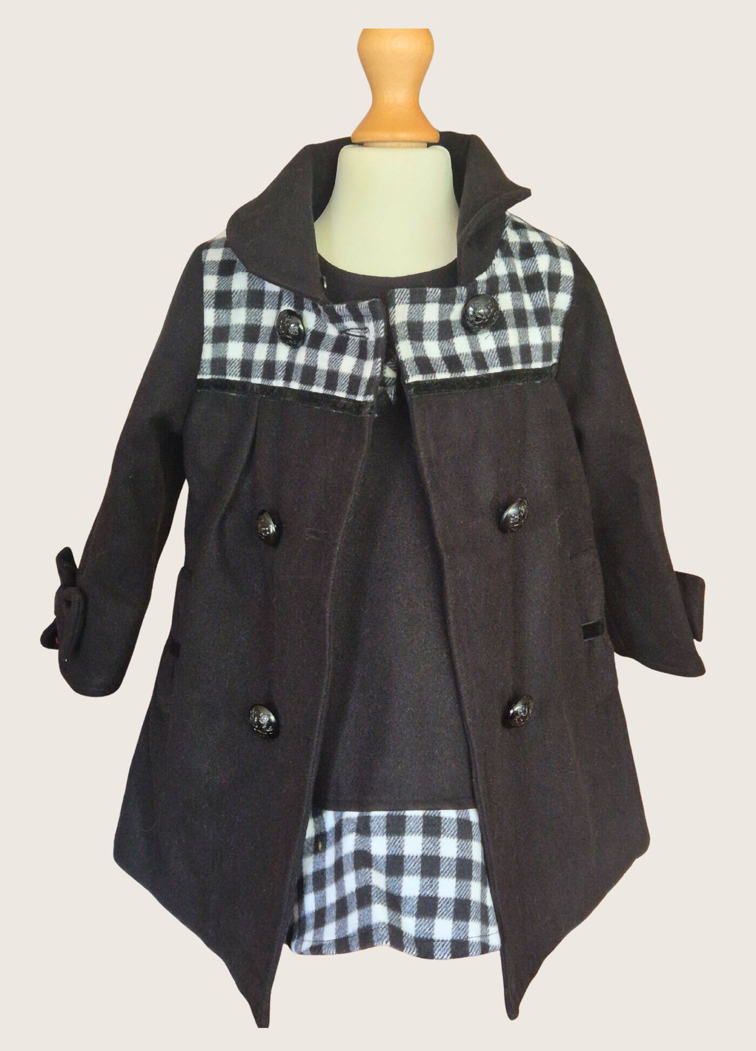 Black coat with plaid pattern on a mannequin against a plain background